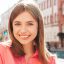 Closeup portrait of young beautiful smiling hipster woman in trendy summer clothes. Sexy carefree woman posing on the street background at sunset. Positive model outdoors.Biting her lips