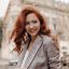 Curly lady in eyeglasses smiling and posing outside